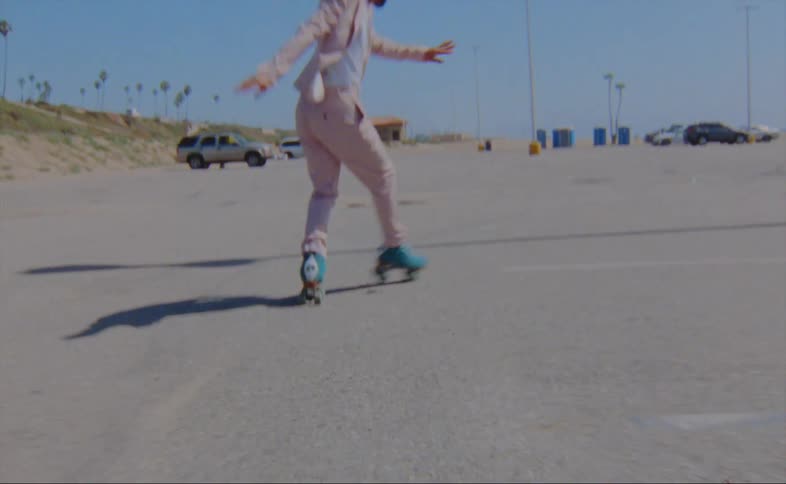 A man is skating in a parking lot during the spring
