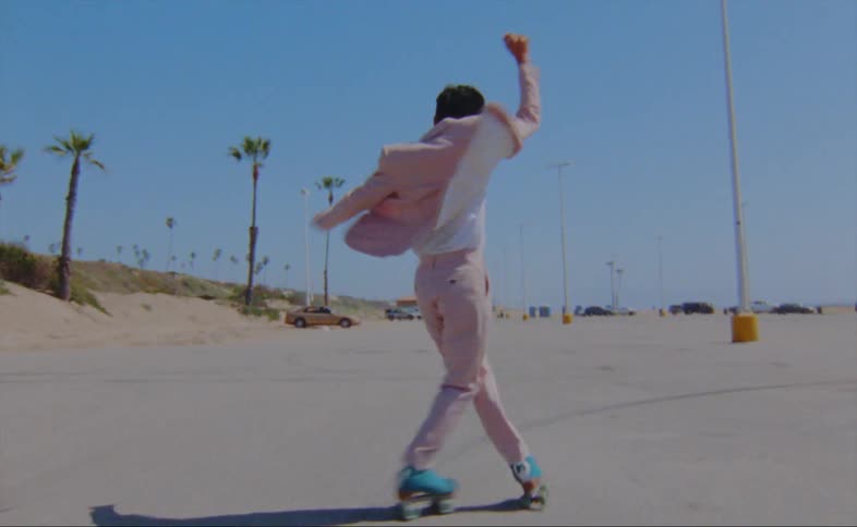 A man on roller skates dances and skates in a parking lot