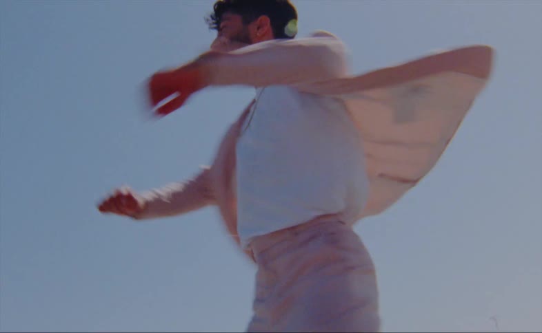 A man spins while dancing outdoors on a sunny day