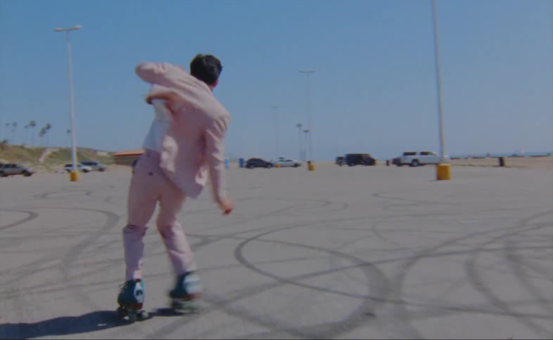 A man is skating outdoors in a parking lot