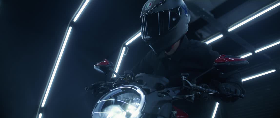 A man is getting onto a motorcycle and wearing a helmet