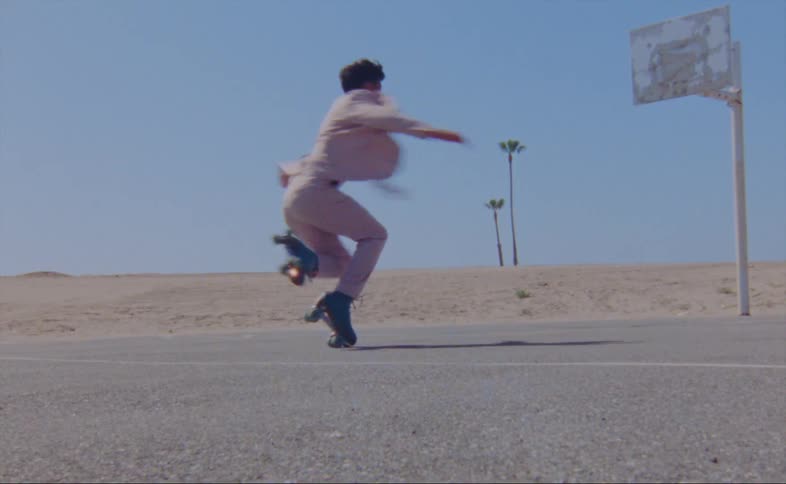 Man with pink suit on turquois roller skates moves over a hard surface in the court