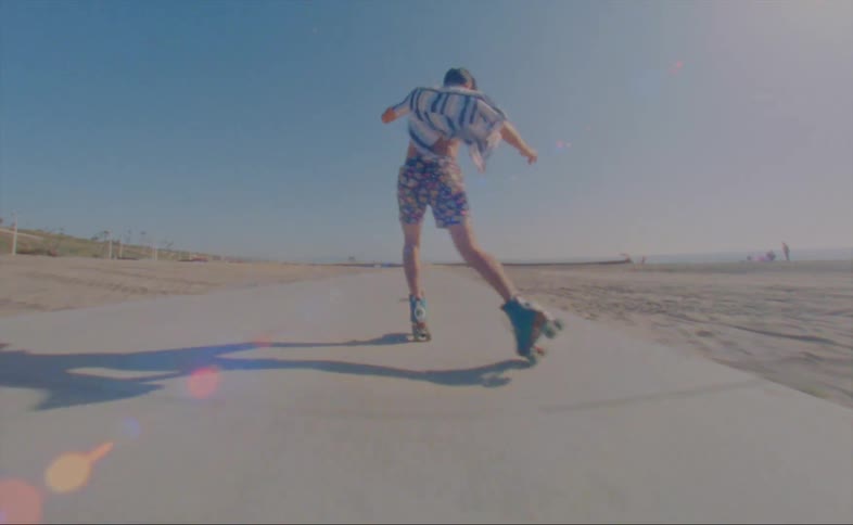 A man is skating outdoors on a street by the beach