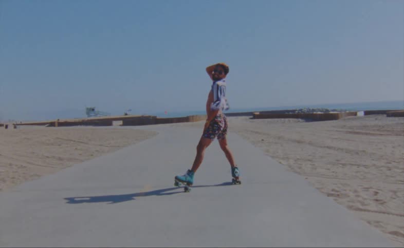 A man dances while roller skating on the beach