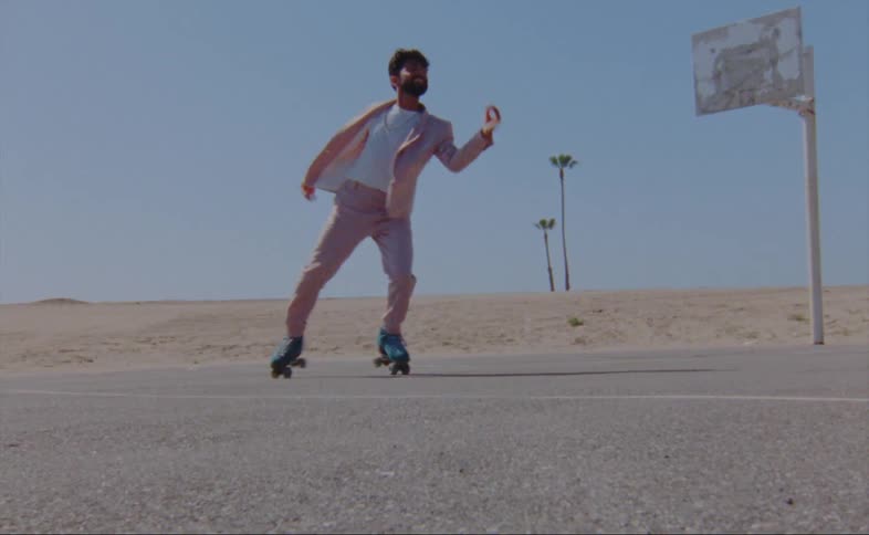 Man dances on roller skates on basketball court near sandy stretch of land
