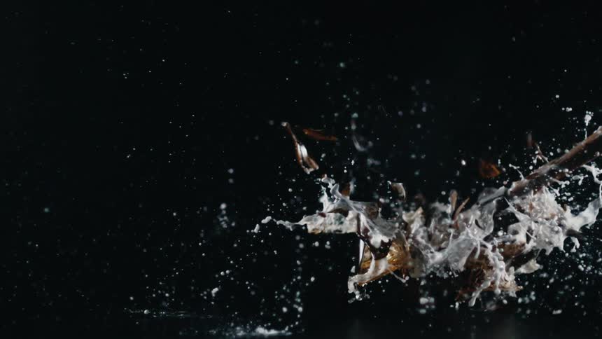 A glass bottle full of beer is smashed with a hammer
