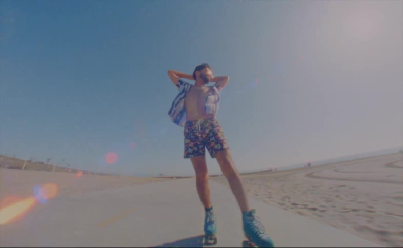 Man roller skates backwards on path through sand