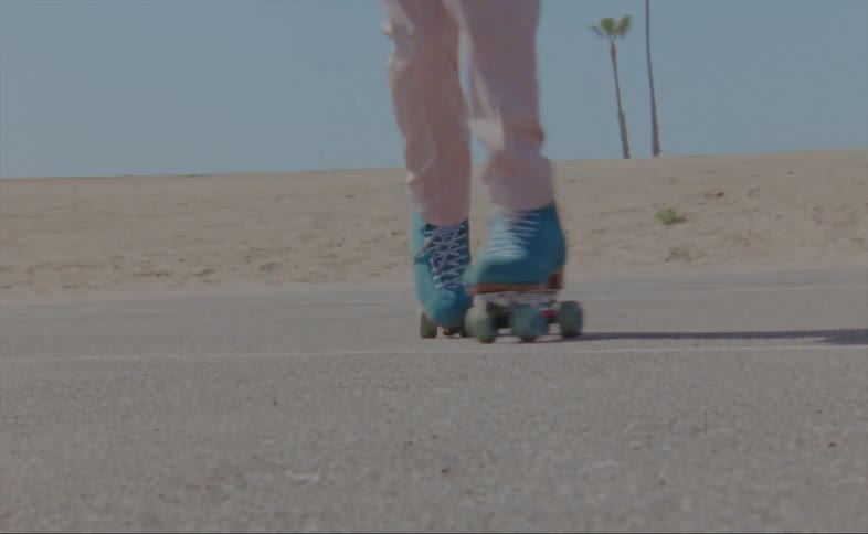 Person wearing pink pants dancing in blue roller skates at the beach