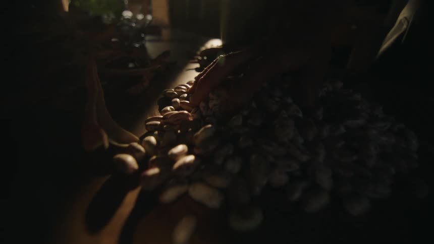 A man runs his hand through a pile of potatoes on a table