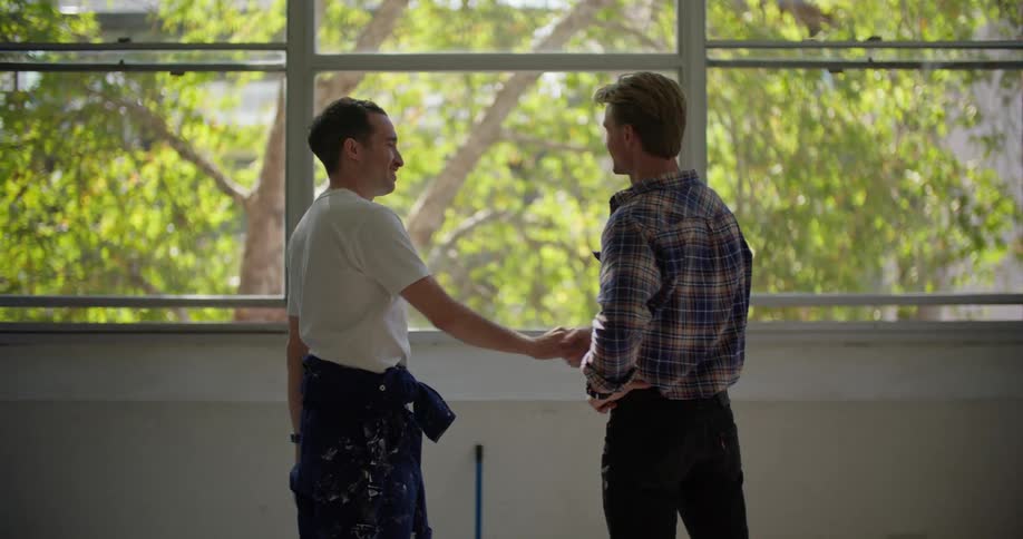 Two friends shake hands after finishing painting a room