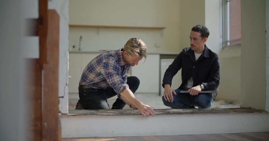 Two men take measurements while remodeling an apartment