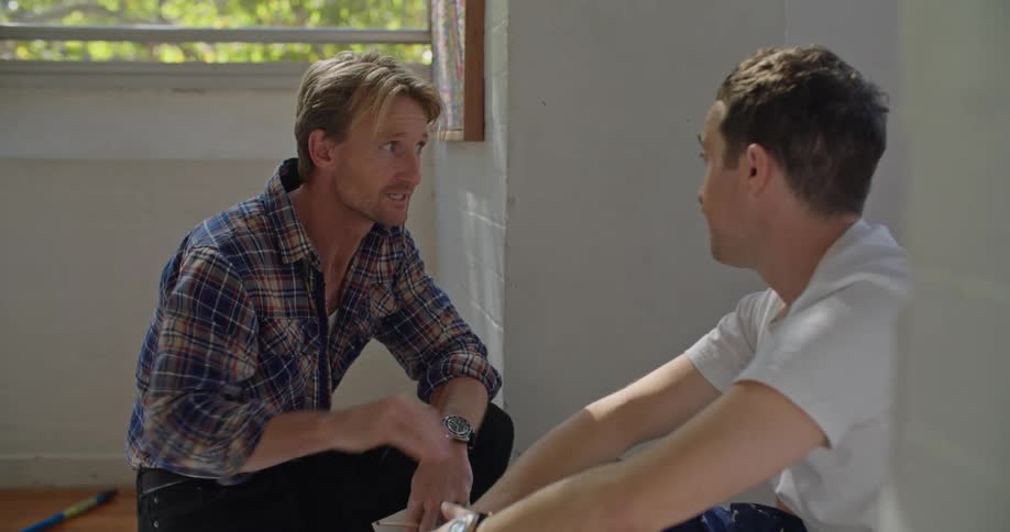 Two men talk and look through papers together