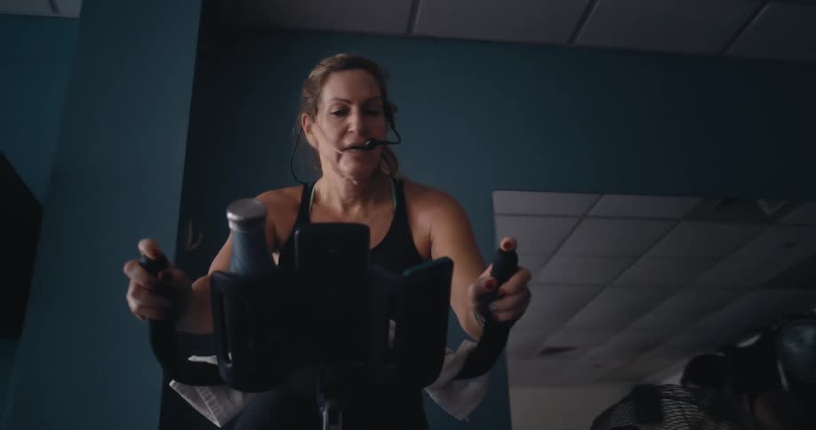 Woman wearing a microphone uses and exercise machine in a gym