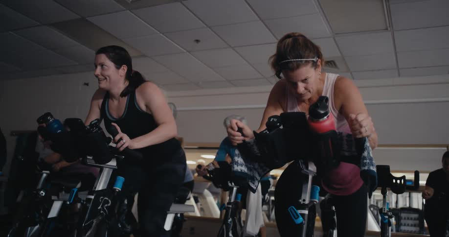 A group of people working out on stationary bikes in a gym