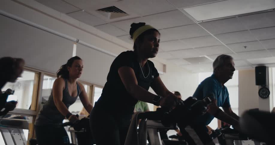 People are in a gym working out on exercise bikes