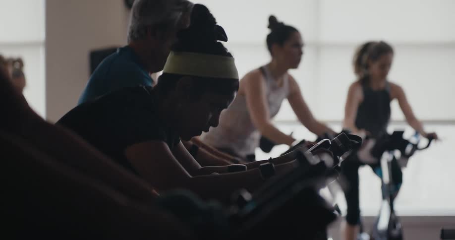 Women and men work out and ride exercise bikes in the gym