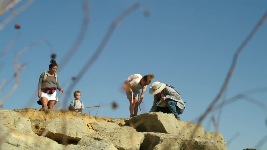Family of four exploring the rocks on a small hill while camping