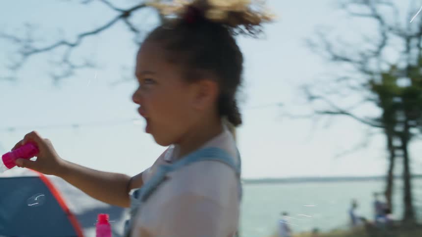 A child waves bubbles around the camp