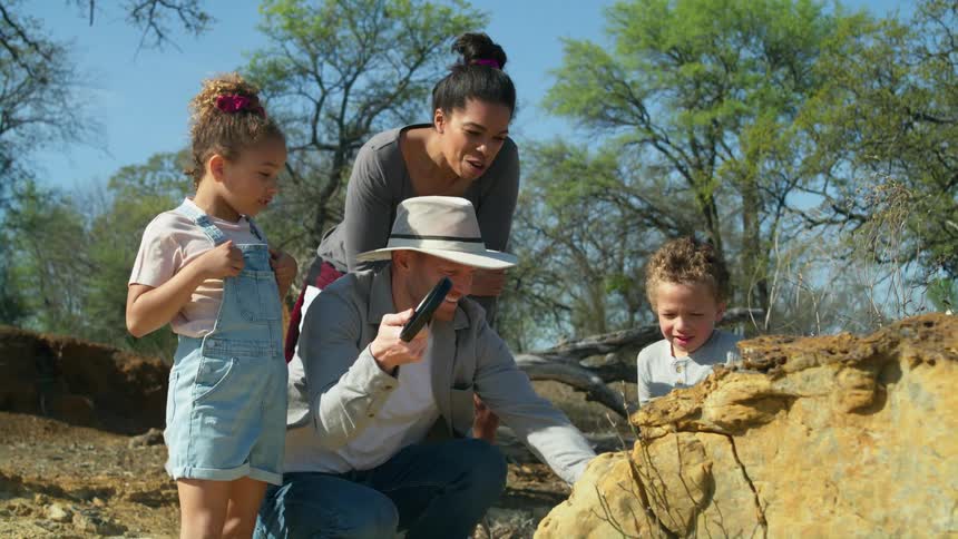 A family is in aremote area looking at a large boulder