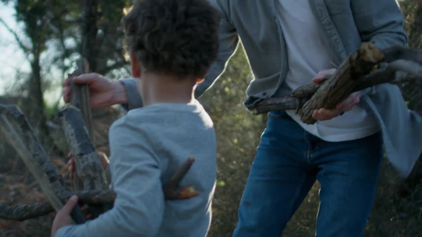 Father and son picking up wood for a campfire in the morning