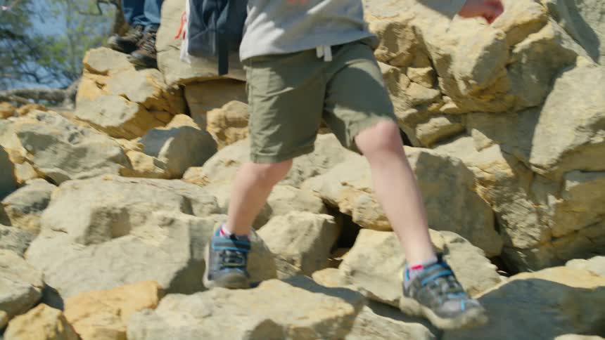 Some children and an adult make their way down a rocky cliff