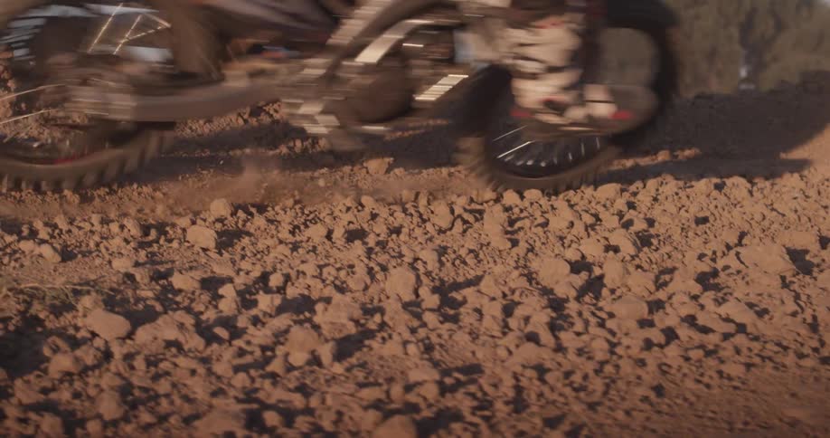 A dirt bike speeds through an area while kicking up dust