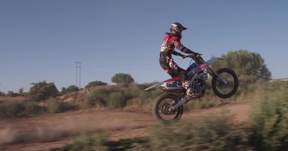 A man pops a wheelie on a dirt bike