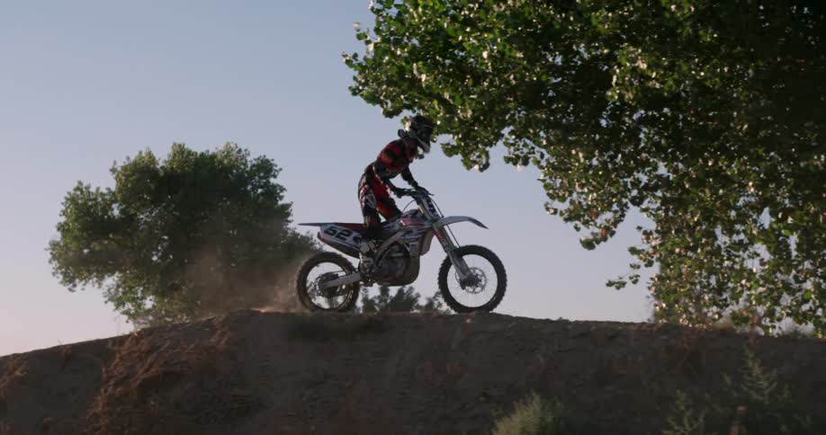 A person rides his motorcycle over some dirt mounds