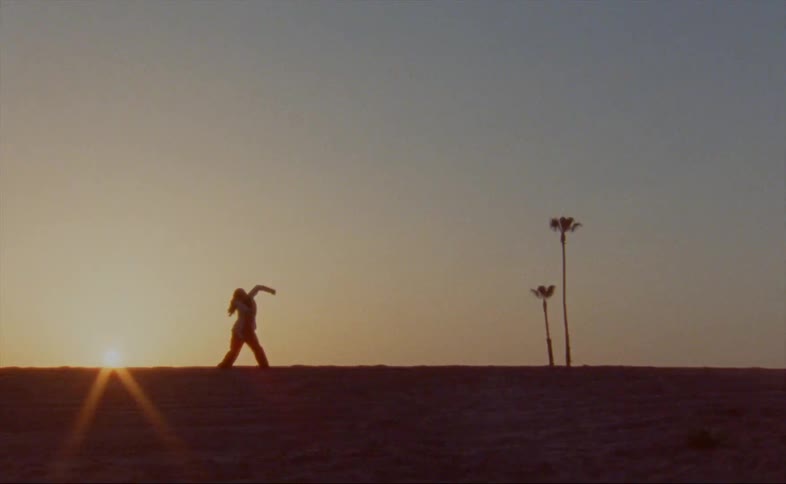 Woman dances silhouetted against setting sun