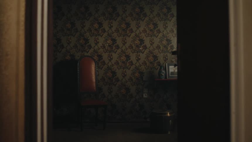 Chair sits against wallpapered wall an near a small table