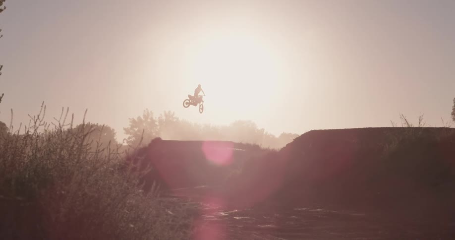 A person is doing very high jumps on a dirt bike
