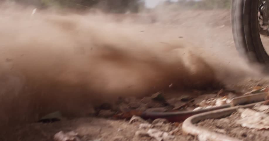 A person rides a motorbike on a dusty road