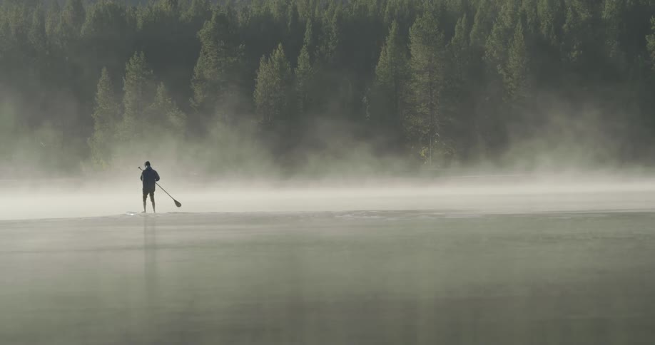 A person is rowing on a board in a lake