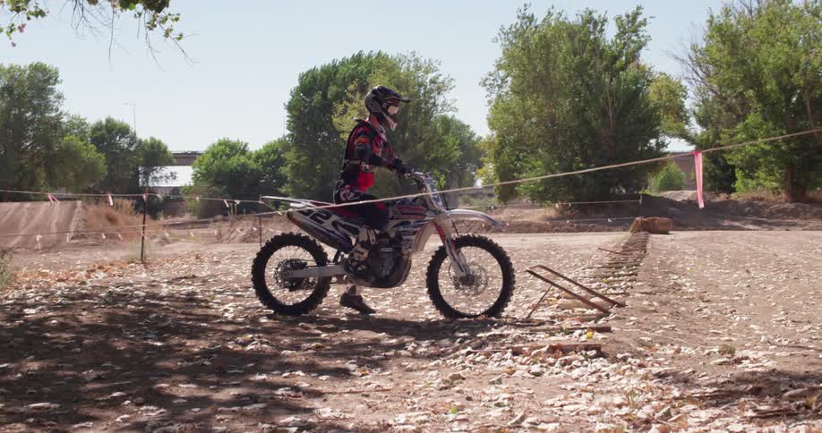 A person gets on a dirt bike and starts it up