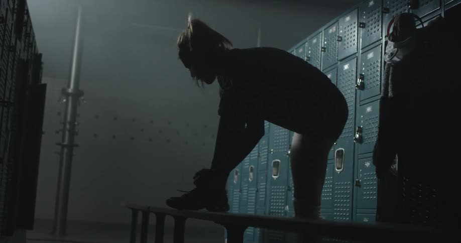 A woman ties her shoes in a locker room