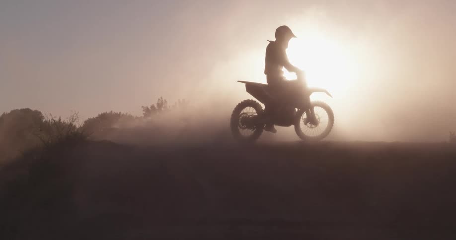A dirt biker makes a turn at sunset
