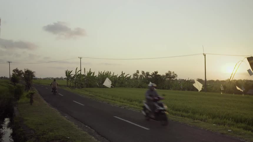 Motorcycles drive down a road on a windy day