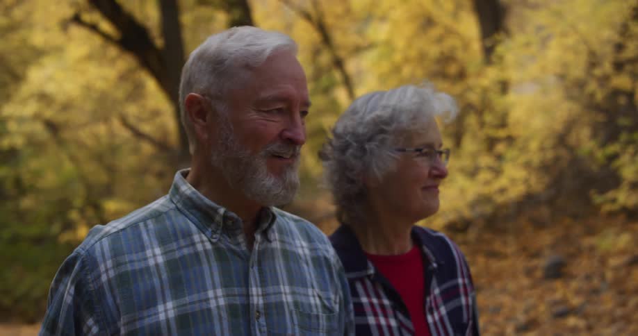A couple smile while walking through the woods together