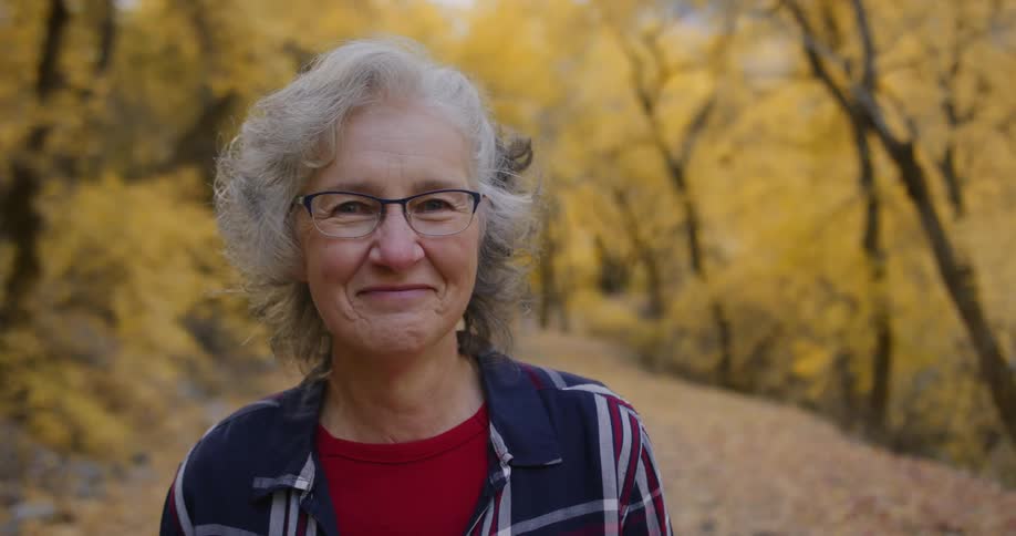 A woman smiles as she stands on a path in the forest