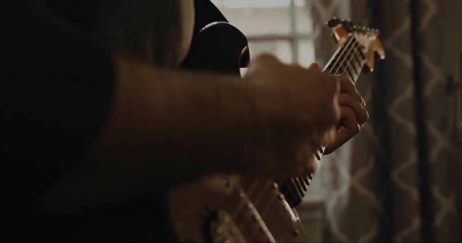 Man strumming an electric guitar on a room at home