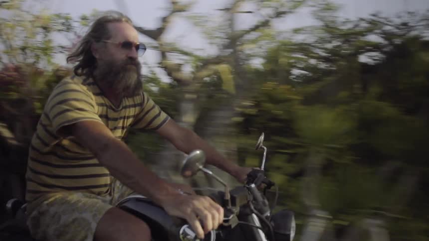A bearded man drives his motorcycle