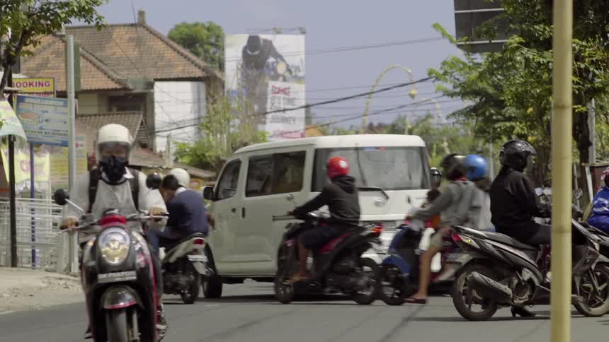 Motorcyclists ride on a busy town street