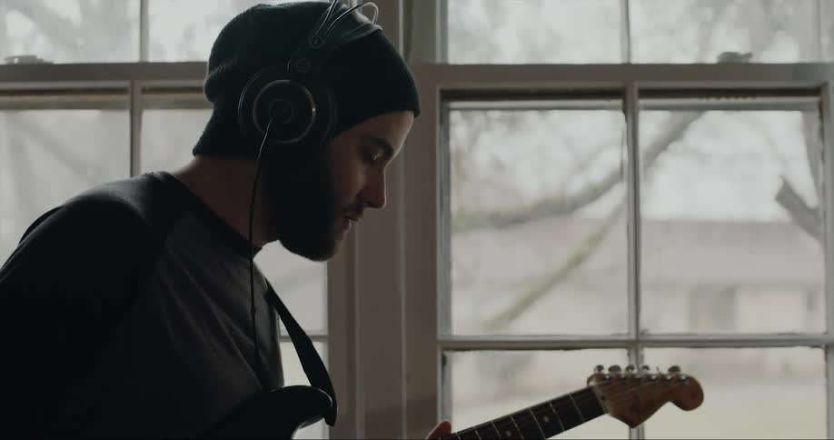 A man playing a guitar in a house