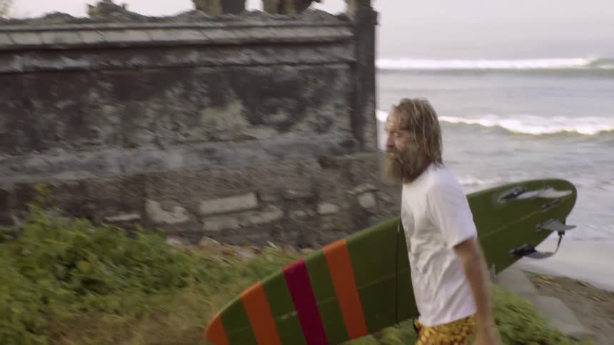 Man holding surfboard walking away from the water