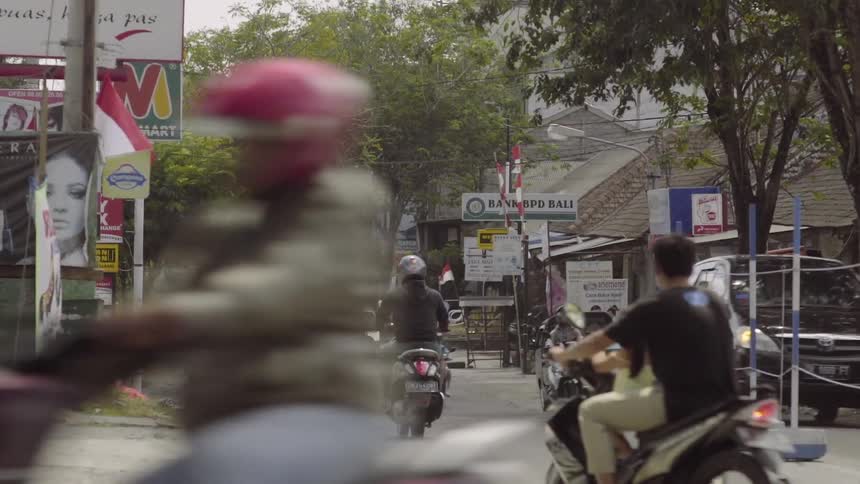Vehicles and pedestrians move along a busy small town street in an asian nation