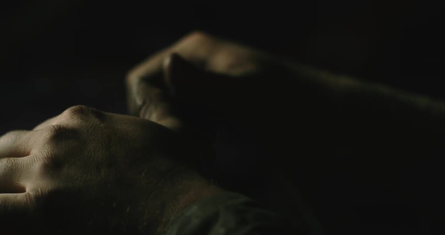 A man is tightly gripping a steering wheel and flexes his hands