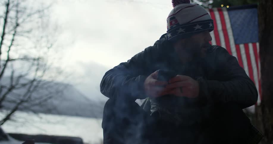 A man is sitting by a campfire