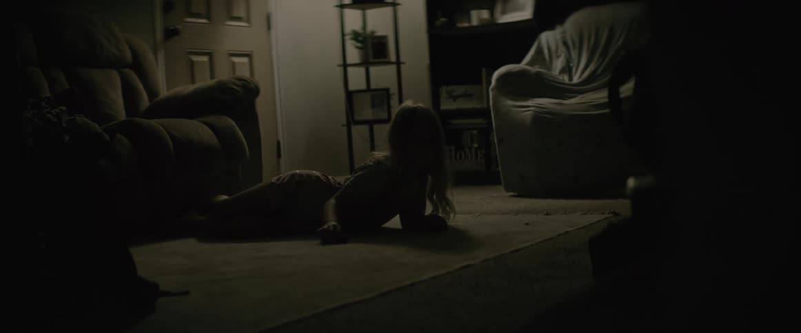 A young girl lies on a rug in a house and plays