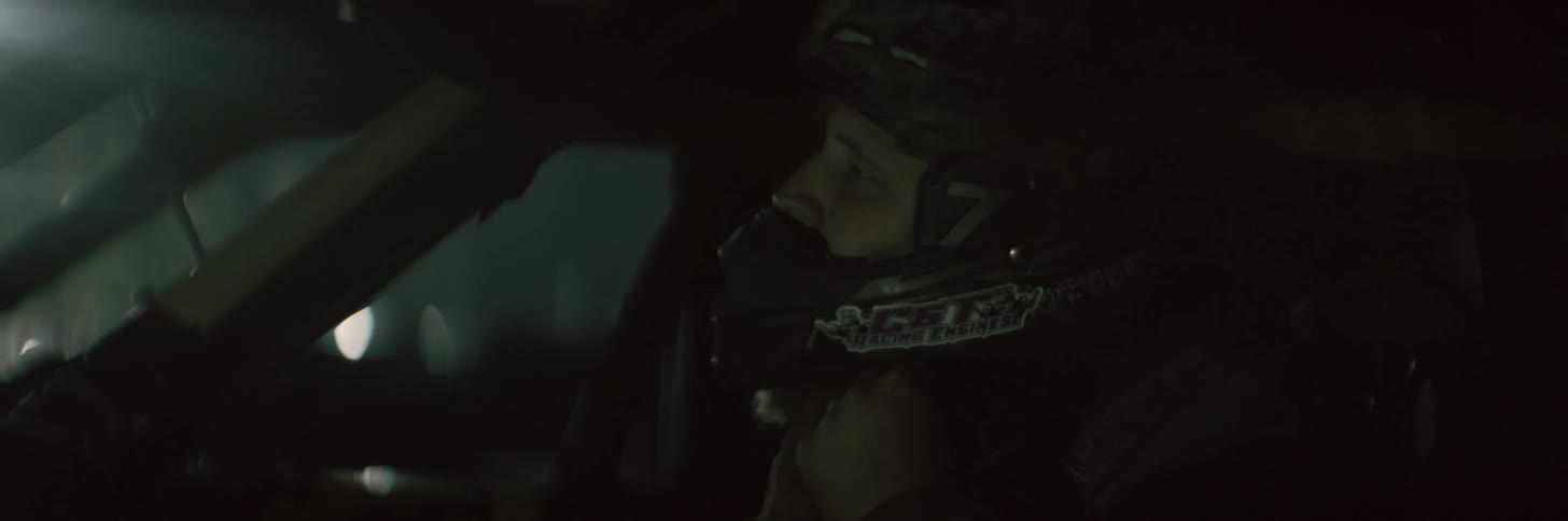 A driver adjusts the strap of his helmet while sitting in a car