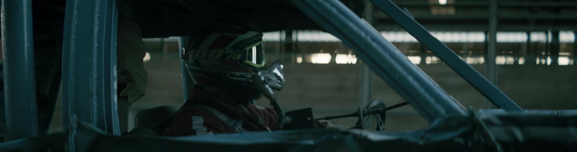 A race car driver sits behind the wheel